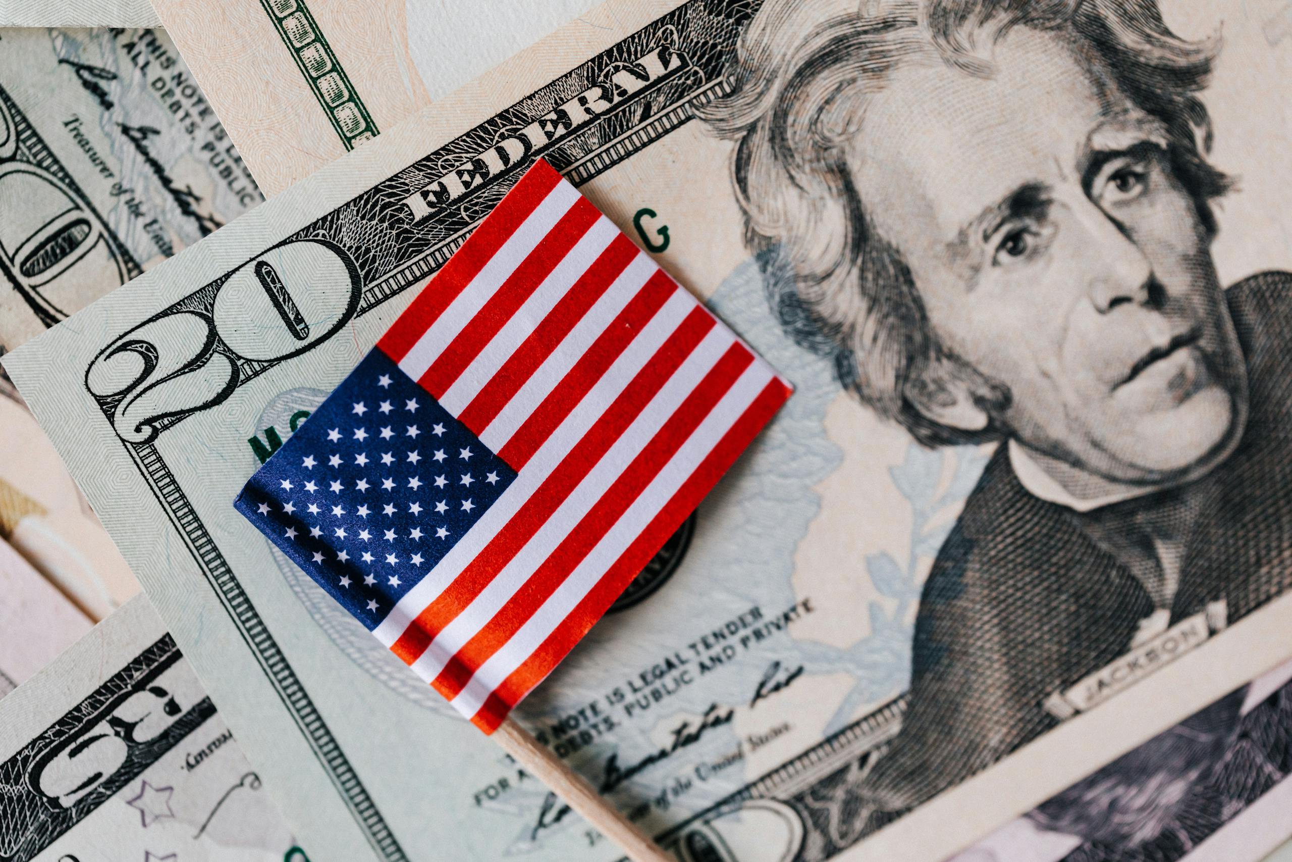 From above of small American flag placed on stack of 20 dollar bills as national currency for business financial operations