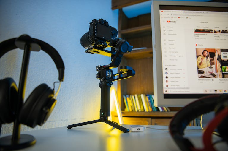 Professional photography setup featuring a camera on a tripod, headphones, and a computer monitor displaying video content.