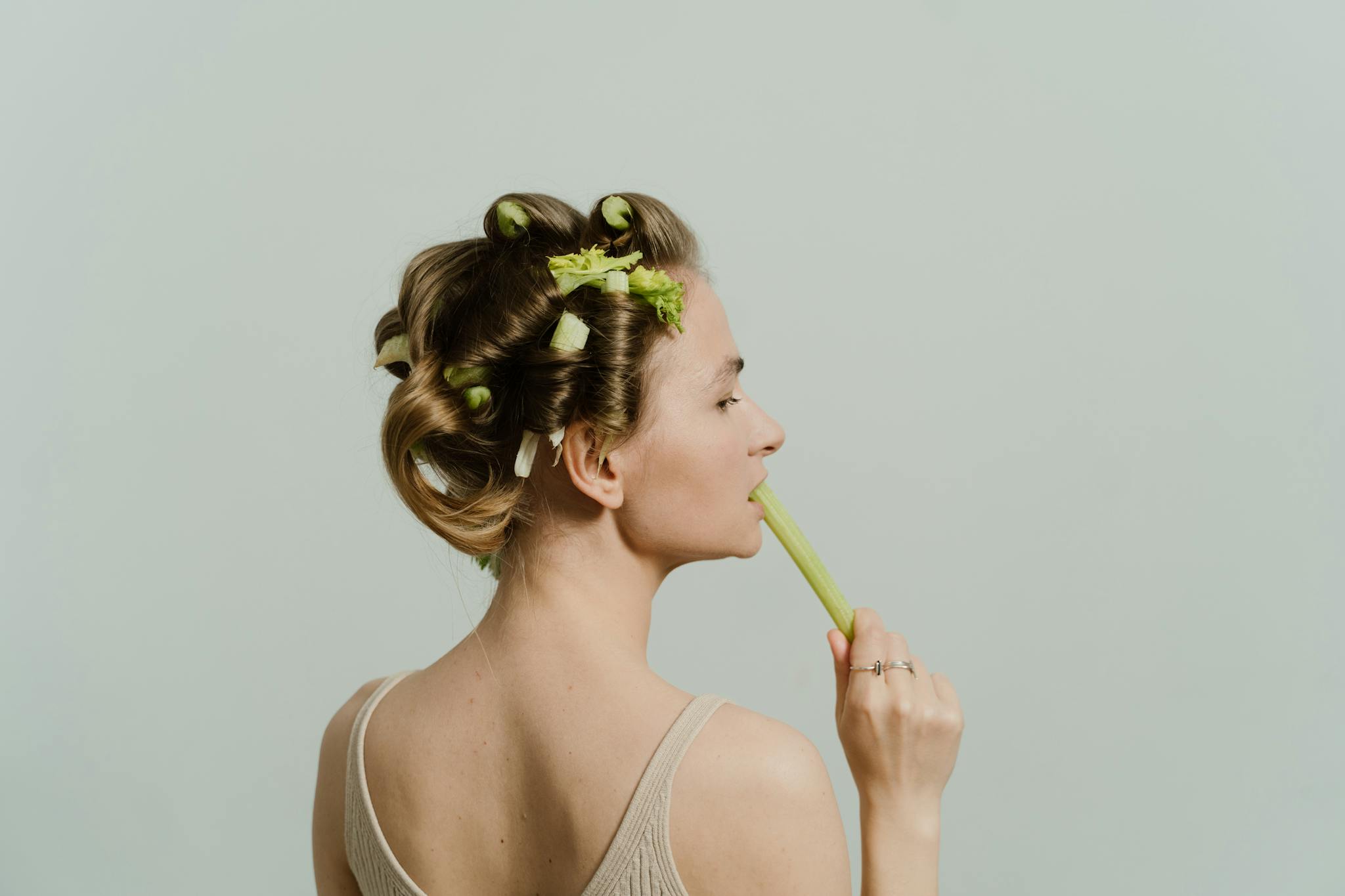 a woman with celery in hair rollers