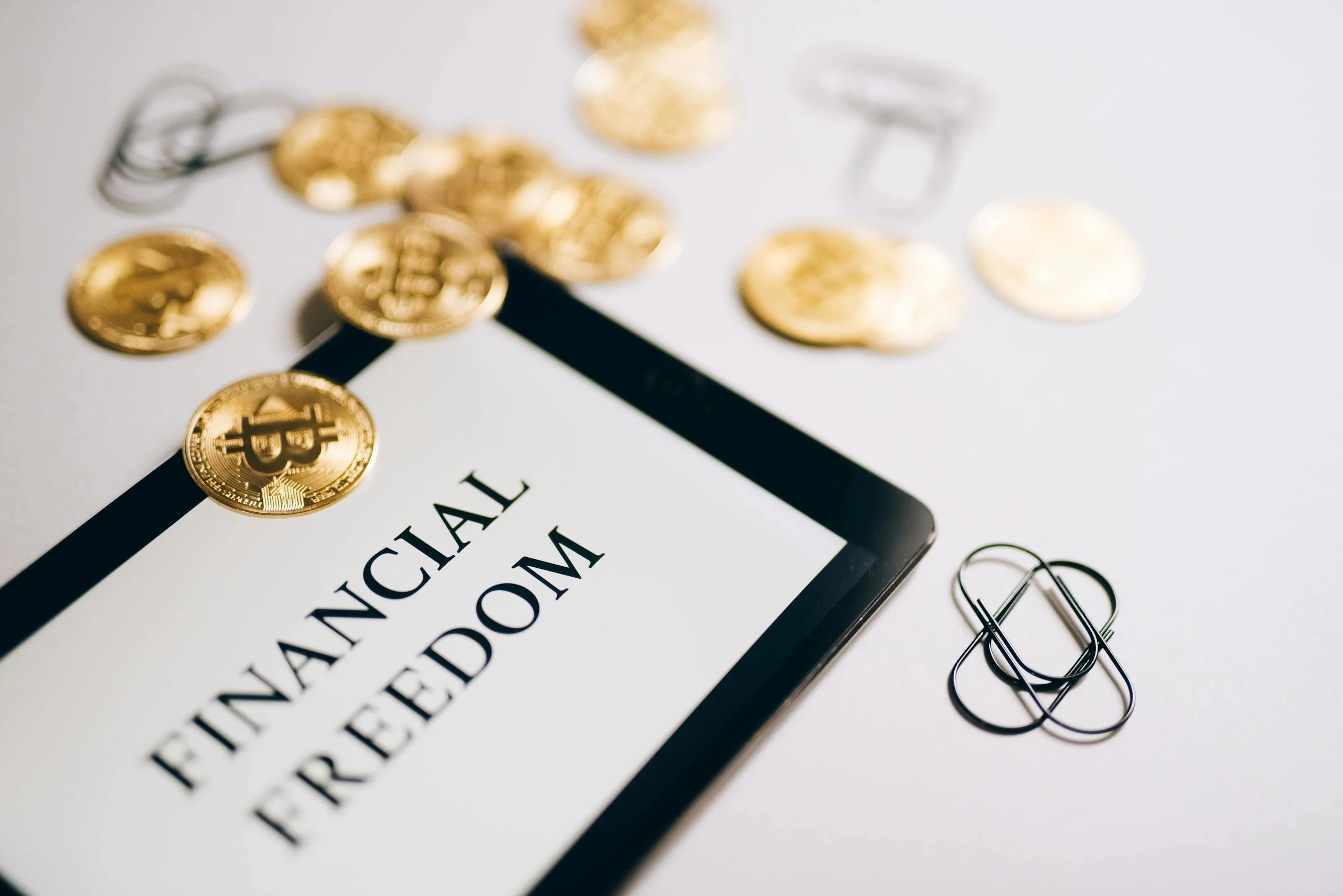 Close-up of Bitcoin coins and an iPad displaying 'Financial Freedom,' symbolizing modern digital savings.